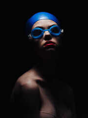 beautiful woman in goggles for swimming and bright makeup red lips black background