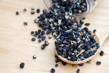 Fototapeta na wymiar Black wolfberries or black goji berries, in a wooden spoon on table. Chinese herbs commonly used in traditional Chinese medicine. Health care concept.