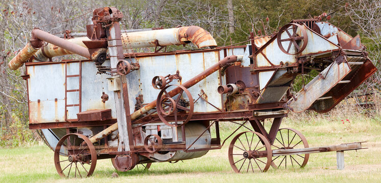 Panoramic image of antique farm machinery for harvest with iron wheels