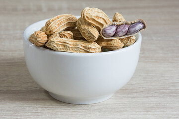 Group of peanut in white cup on wooden table background,copy space.