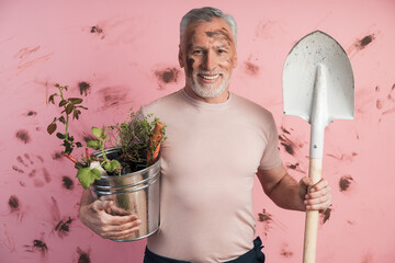 Senior man, gardener with a shovel and a bucket in his hands. Cute elderly man is engaged in...