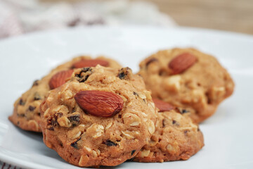 Closeup Almond cookies or healthy snacks stack on a white plate with a blurred background.