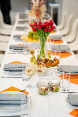 vase with a bouquet of red tulips on the festive table. serving the table with appetizers, canapes, salads in jars. Catering. restaurant business.