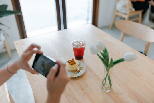 Close up of blogger's hand uses a smartphone to take pictures of food.