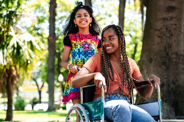 Woman in a wheelchair at the park with her daughter.