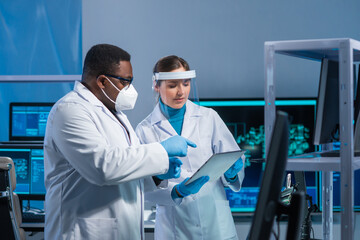 Diverse team of microelectronic engineers discuss current developments in a science lab. Workplace...