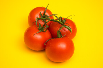 Red ripe tomatoes on a yellow background. Preparing a salad of vegetables. Natural products from the beds.