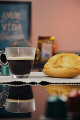 Transparent cup of coffee and bread and butter on the plate on black table with reflection.