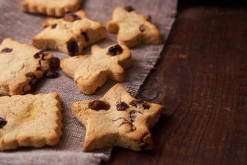 Healthy homemade gluten-free, lactose-free cookies of various shapes without sugar with raisins and chocolate on a dark brown wooden background