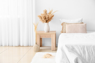 Wooden table with vase in interior of bedroom