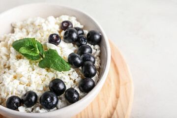 Bowl of natural cottage cheese with blueberries on light background