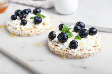 Crispbreads with cottage cheese and blueberries on light background