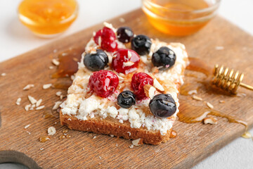 Tasty sandwiches with cottage cheese and berries on wooden board