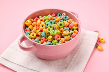 Bowl with crispy cereal rings on color background
