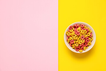 Bowl with tasty cereal rings on color background
