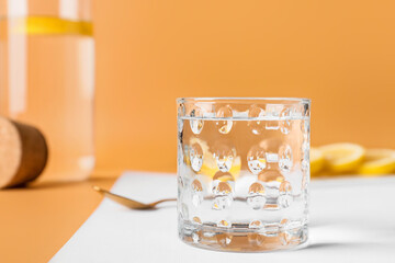 Glass of water and lemon on color background