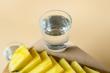 Board with glass of water and pineapple on color background