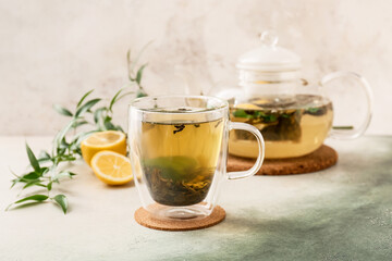 Cup of hot green tea with lemon on light background