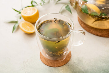 Cup of hot green tea with lemon on light background