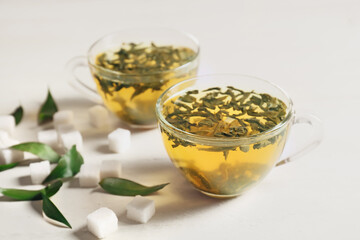 Cups of hot green tea on light background