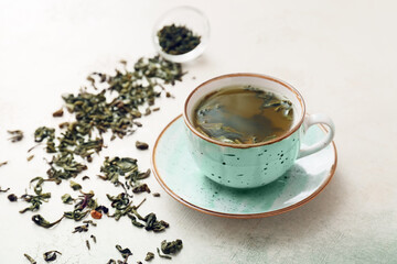 Cup of hot green tea on light background