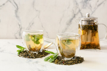 Cups of hot green tea on light background