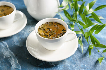 Cup of hot green tea on color background