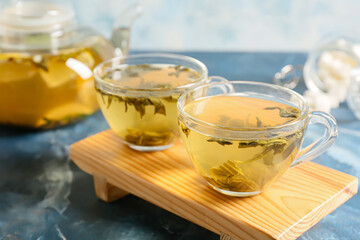 Stand with cups of green tea on color background