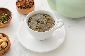 Cup of hot green tea on light background