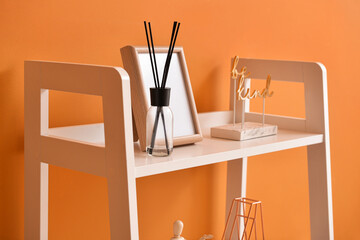 Modern shelf unit with decor near color wall in room