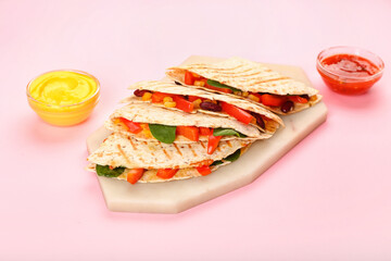 Board with tasty vegetarian quesadillas and sauces on color background