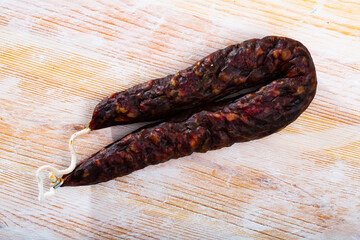 Traditional French dry cured sausage laced with liver on wooden board..