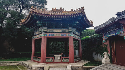 A man sleeping while leaning against a table in a small pavilion in the nearby of Forbidden City in...