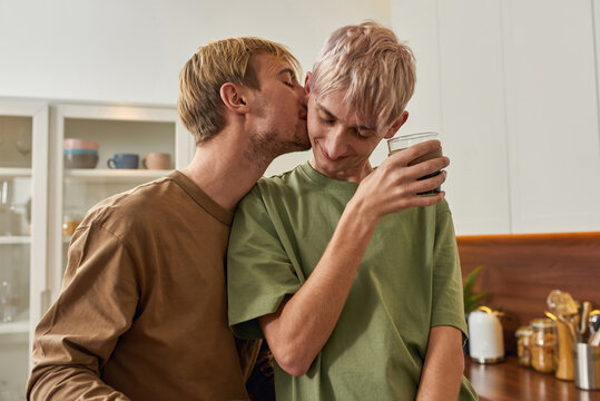 Smiling young caucasian gay pair kissing and hugging