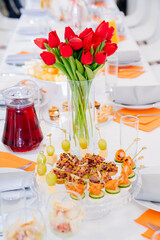 vase with a bouquet of red tulips on the festive table. serving the table with appetizers, canapes, salads in jars. Catering. restaurant business.