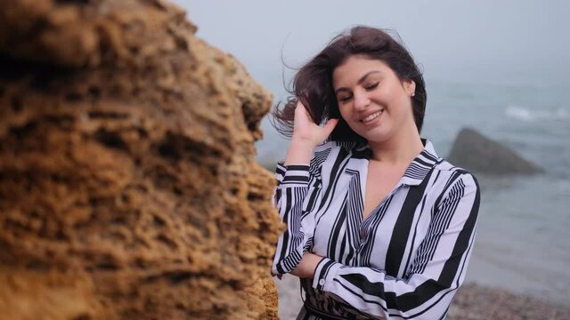 Beautiful young woman stands at rock resting. Gorgeous style brunette female