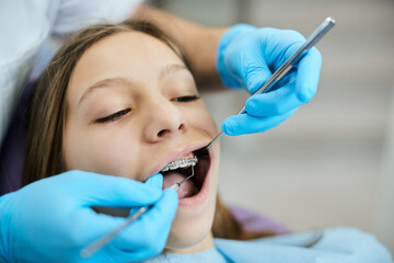 Little girl having her braces checked by orthodontist at dentist's office.