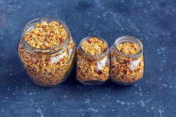 Freshly baked granola, muesli from oat flakes, varius of nuts, honey, pumpkin seeds in glass jar. Home cooking healthy vegetarian snack. Homemade food concept. Keto diet.