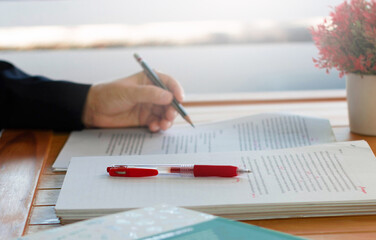 red pen on blurred paperwork and books