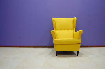 One yellow armchair in roow with blue walls. Minimalism in interior design. Rest concept.