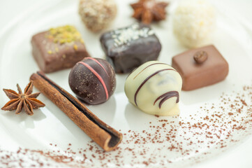 Chocolates, cinnamon stick and star anise are on a white plate. These are lovely chocolates.