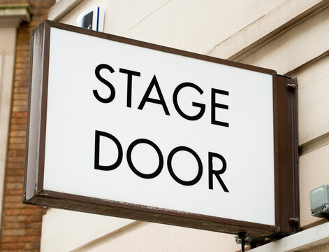Low angle view of STAGE DOOR sign attached to the exterior wall of theatre in London's West End.