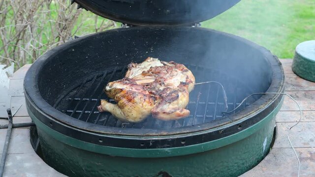Butterflied chicken cooking on a kamado style ceramic grill with digital temperature probe