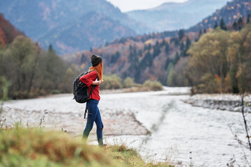Obraz premium woman in a red sweater with a backpack in the mountains on nature near the river pond lake