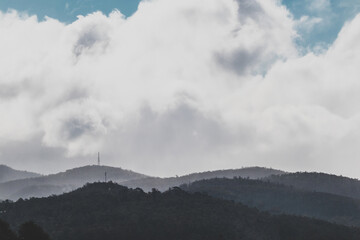 contrasty sky with thick clouds and intense sunlight peeking through them with mountains in the background