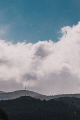 contrasty sky with thick clouds and intense sunlight peeking through them with mountains in the background