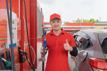Portrait of a Caucasian man, people, worker showing thumbs up, filling up fuel by using petrol pump...