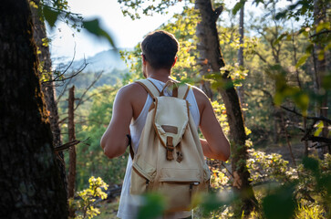 Man Traveler with backpack hiking outdoor in summer sunset forest