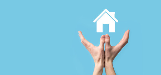 Male hand holding house icon on blue background. Property insurance and security concept.Real estate concept.
