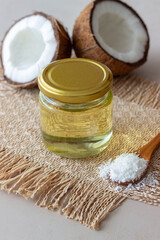 Coconut oil in a jar and fresh coconuts on a beige background. Natural cosmetics.
